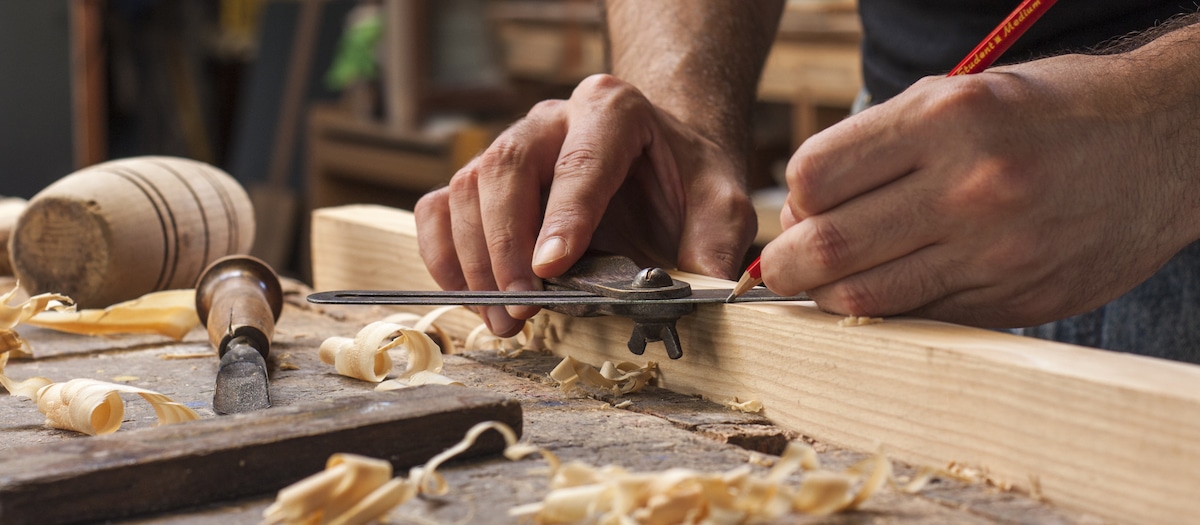 Close up view of carpenter measuring wood with wood shavings in the foreground