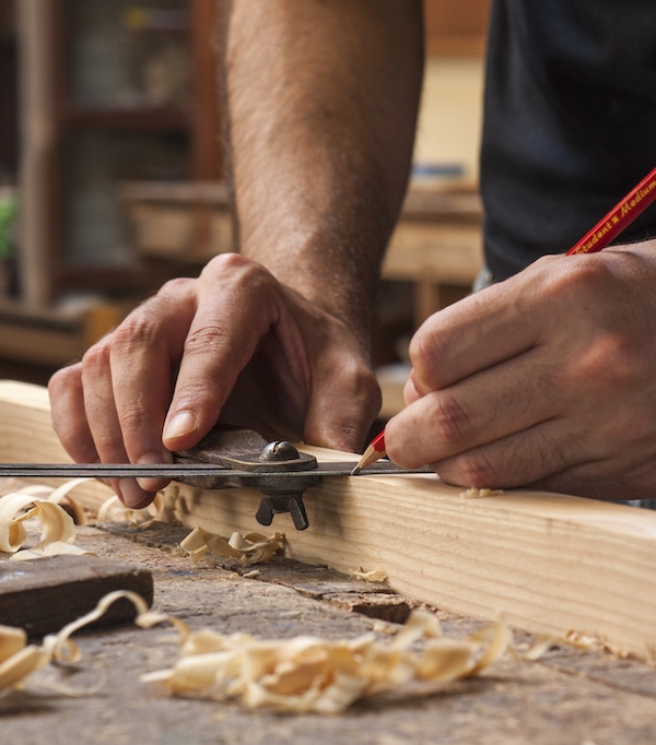Close up view of carpenter measuring wood with wood shavings in the foreground